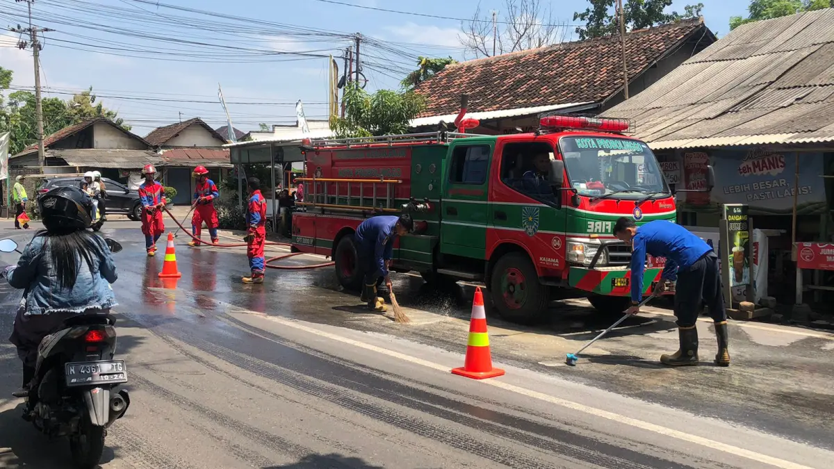SIRAM: Tim Damkar Satpol PP Kota Probolinggo membersihkan ceceran solar di Simpang Tiga Jalan Semeru, Kota Probolinggo, Kamis (19/3). (INNEKE AGUSTIN/JAWA POS RADAR BROMO)