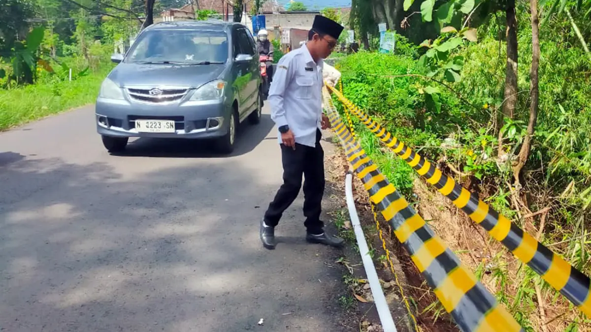 DIPASANG PENANDA: Sekdes Bulukandang Prigen memantau plengsengan curah yang alami longsor. (Rizal Syatori/ Radar Bromo)
