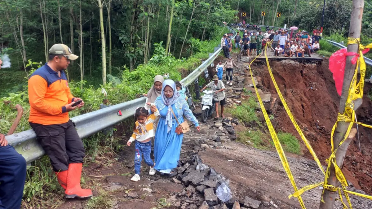 AMBLES: Sejumlah warga melintasi sebagian kecil badan jalan tersisa usai jembatan Duren ambruk. (Inneke Agustin/ Radar Bromo)