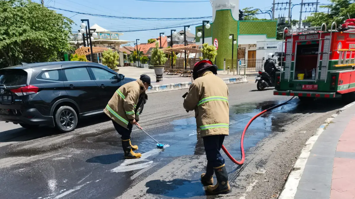 SIRAM: Tim Damkar Satpol PP Kota Probolinggo membersihkan ceceran solar di Bundaran Gladak Serang, Kota Probolinggo, Rabu (1/4). (DAMKAR SATPOL PP KOTA PROBOLINGGO FOR JAWA POS RADAR BROMO)