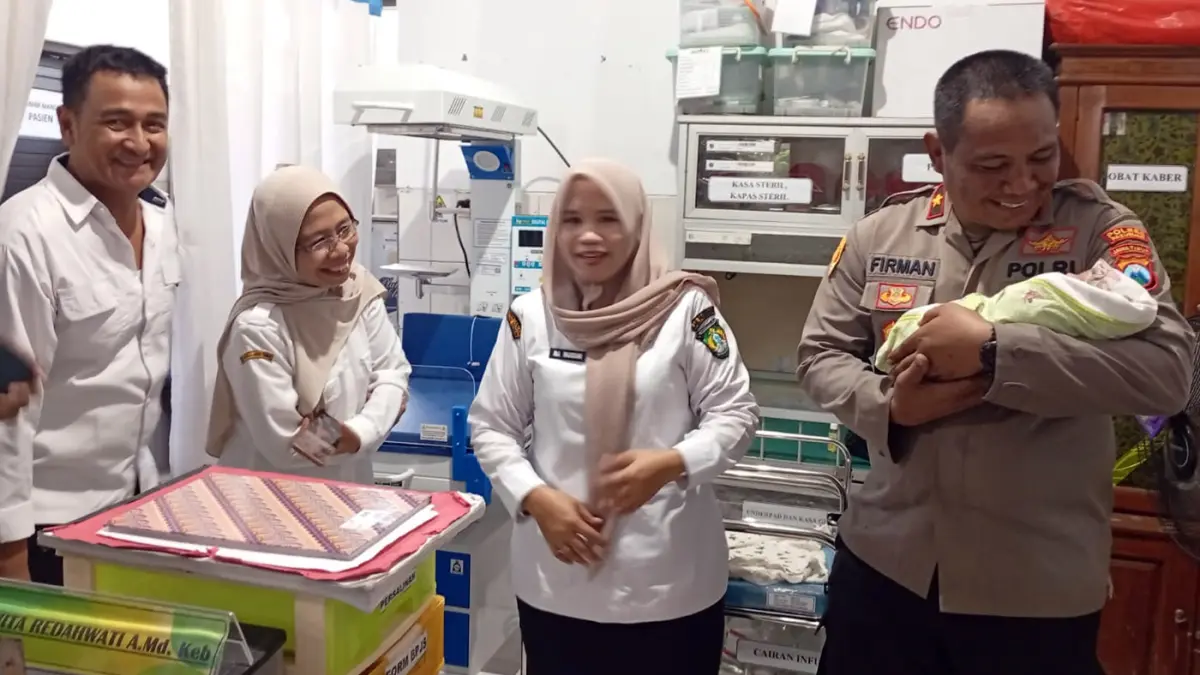 SEHAT: Kapolsek Bangil Kompol Firman menggendong bayi perempuan yang ditemukan di teras rumah warga Kidul Dalem, Bangil, Kabupaten Pasuruan, Rabu (8/4). 