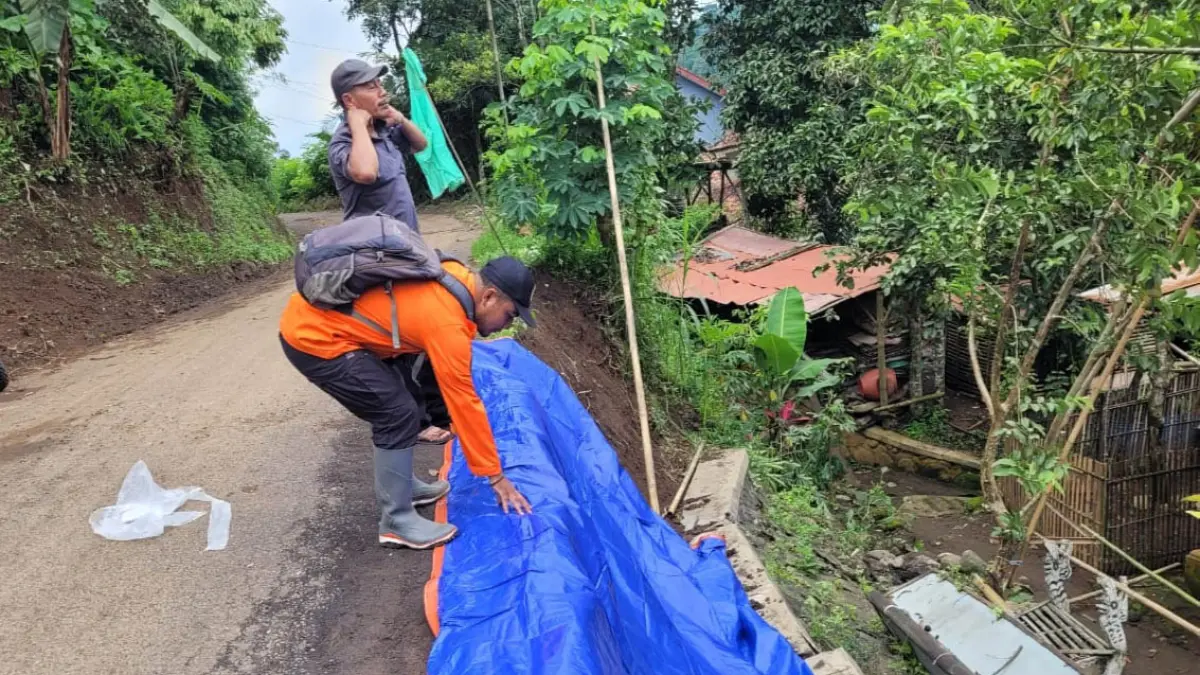 RAWAN: Personel BPBD menutupi longsor dengan terpal di&nbsp;Tiris beberapa waktu lalu. (Foto: dok Jawa Pos Radar Bromo)