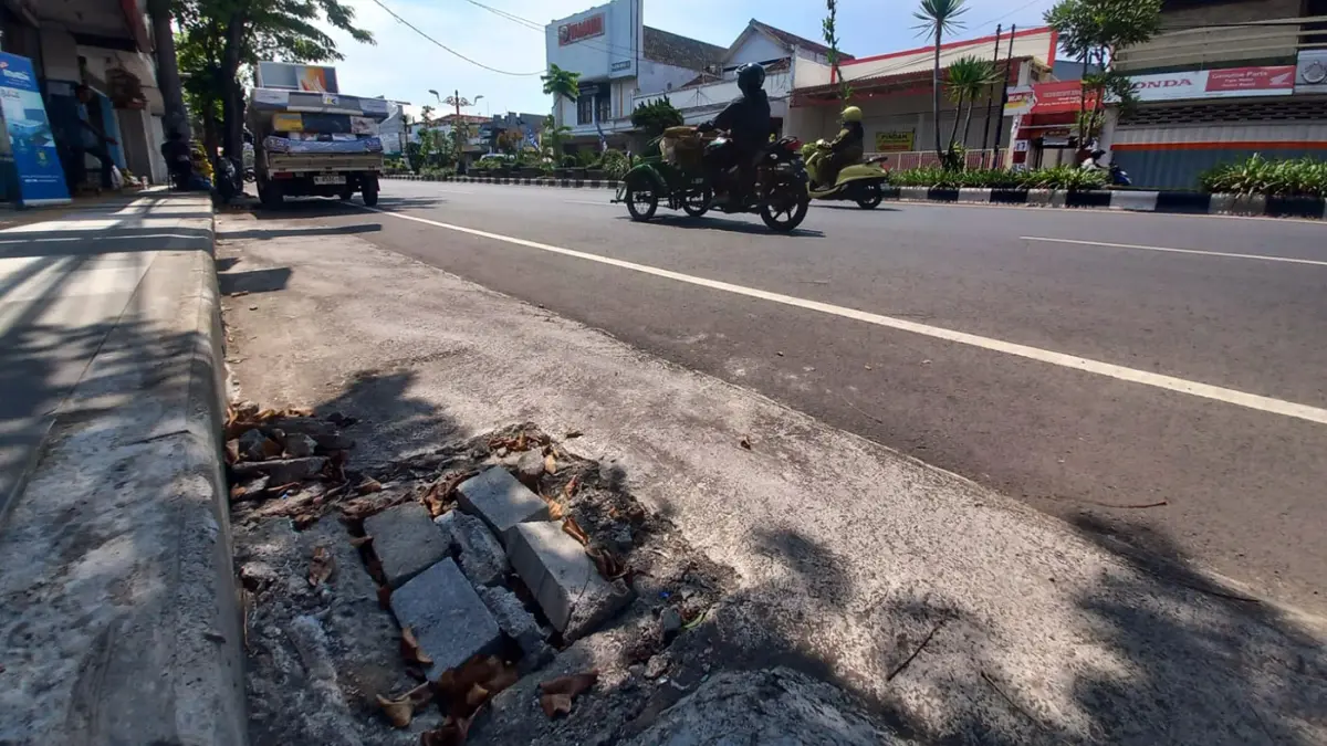 SEMENTARA DITUTUP PAVING: Tiga bak kontrol gorong-gorong di ruas Jalan Panglima Sudirman, Kota Probolinggo, saat ini tanpa penutup besi. Warga menutupnya dengan bongkahan paving dan potongan kayu. (Inneke Agustin/ Radar Bromo)