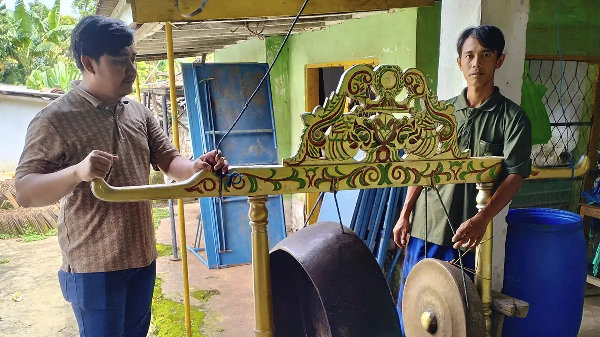 PENINGGALAN: Yusuf Wibisono (kanan) bersama Perangkat Desa Tegalsiwalan Rudi Hariyanto menunjukkan gong peninggalan Bujuk Rawen yang saat ini masih digunakan. (Achmad Arianto/Radar Bromo)
