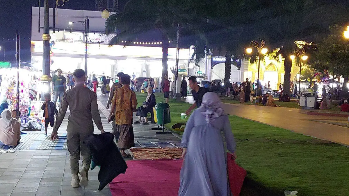 DIAMBIL PAKSA: Personel Satpol PP membawa karpet milik PKL yang berjualan di trotoar dalam Alun-alun, Sabtu (11/4) malam.( Foto : Satpol PP Kota Pasuruan for Jawa Pos Radar Bromo)