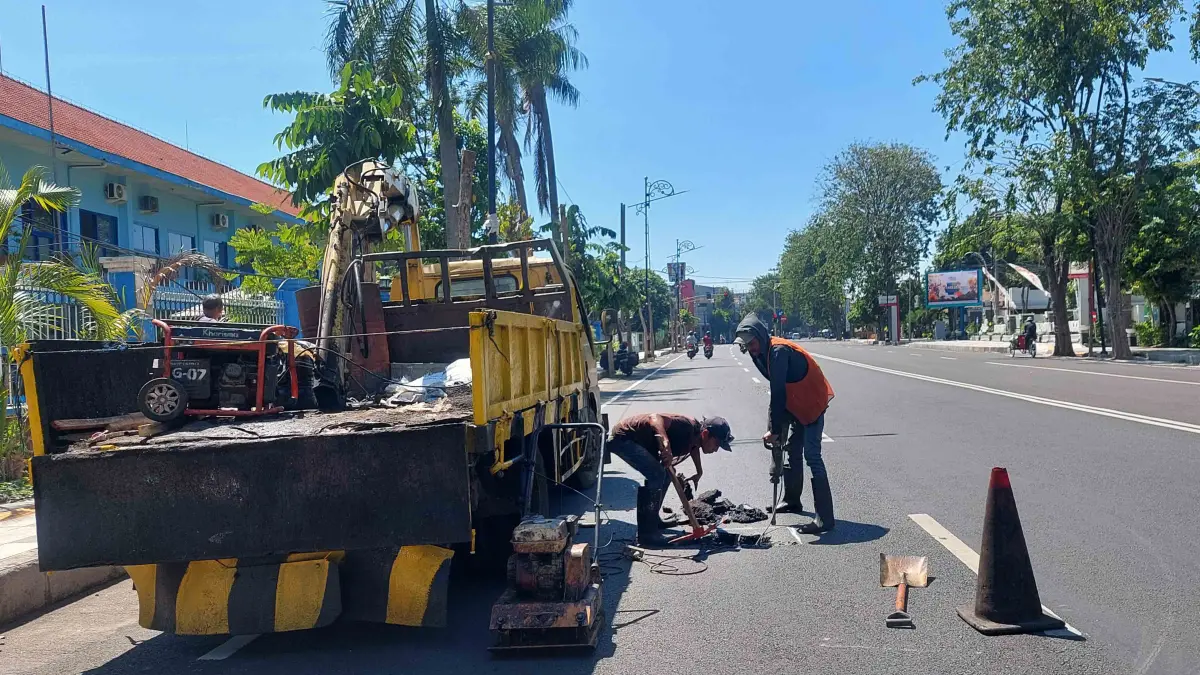 DIPERBAIKI: Sejumlah pekerja memperbaiki aspal jalan yang ambles di Jalan Pangsud Kota Probolinggo, Senin (13/4). (ARIF MASHUDI/JAWA POS RADAR BROMO)