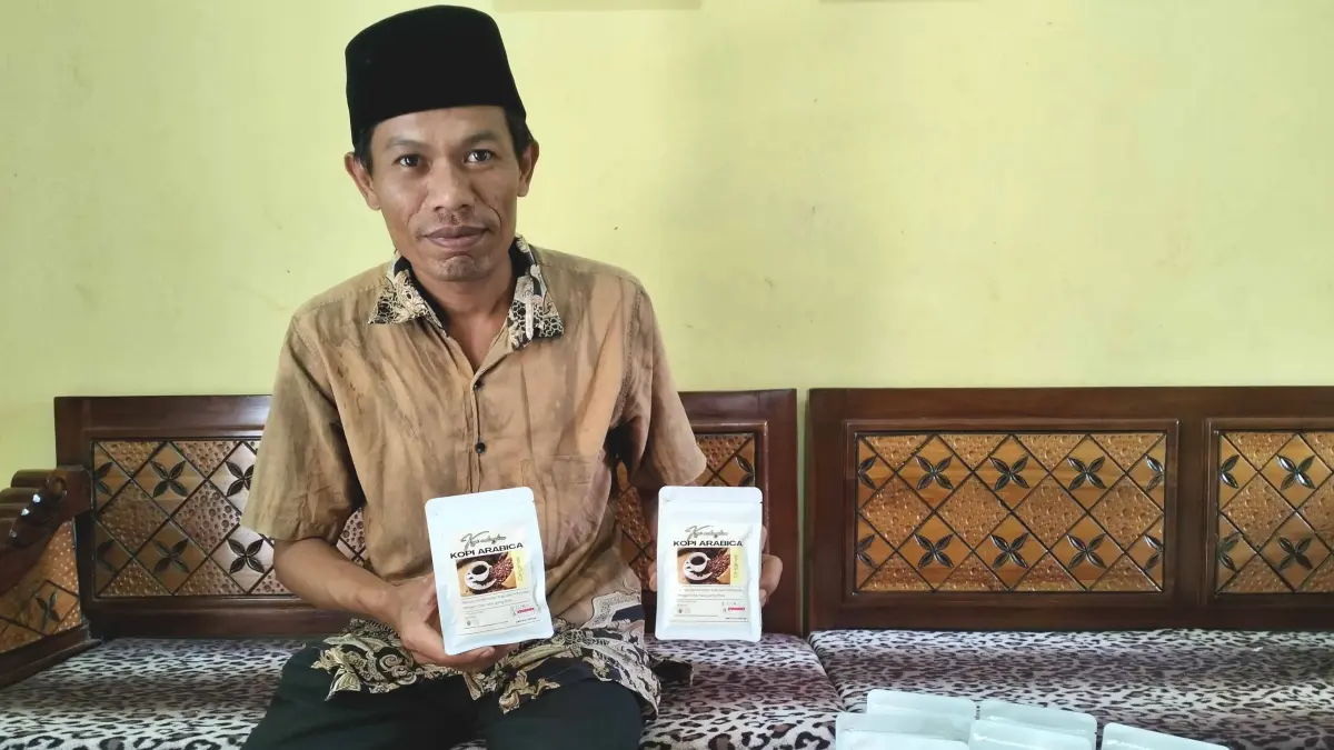 UNGGULAN: Bendahara Desa Andungbiru Agus Santoso menunjukkan kemasan kopi arabika original siap seduh yang diproduksi BUMDes Maju Bersama Andungbiru. (ACHMAD ARIANTO/JAWA POS RADAR BROMO)