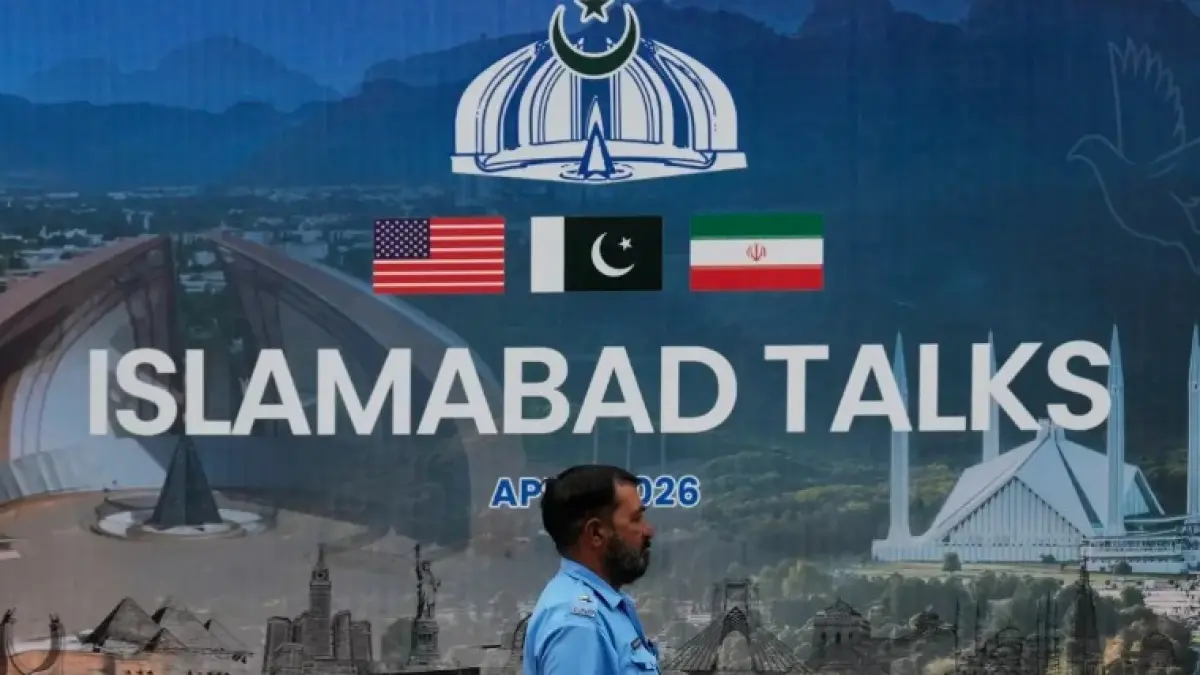 A police officer walks past a billboard regarding the United States and Iran negotiations, outside a media facilitation center in Islamabad, Pakistan, Saturday, April 11, 2026. (AP Photo/Anjum Naveed)