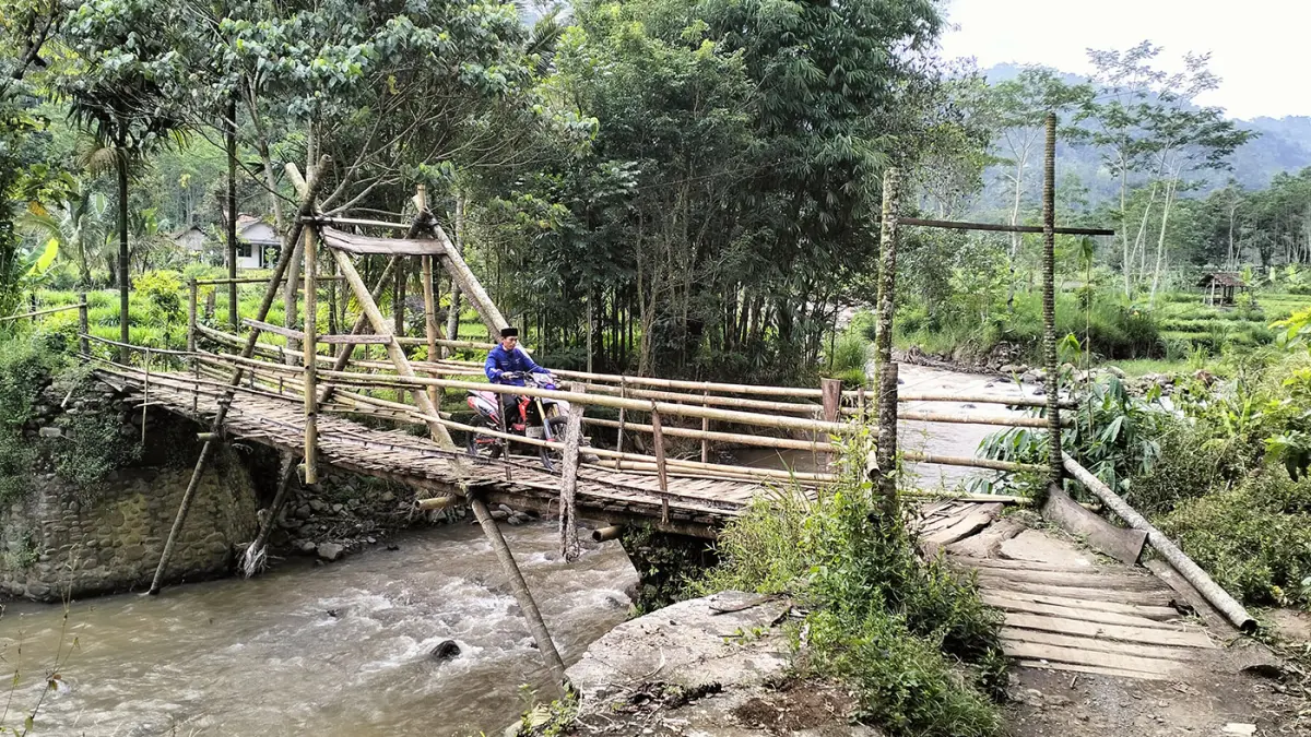 DARURAT: Warga melintas di sebuah jembatan semipermanen menyeberangi Sungai Kedaton di Desa Andungbiru, Kecamatan Tiris, Kabupaten Probolinggo. Jembatan hanya bisa dilintasi motor dan pejalan kaki. (Achmad Arianto/ Radar Bromo)