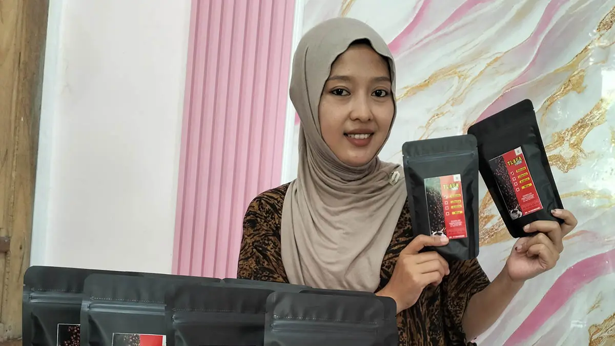 PRODUK LOKAL: Warga Desa Tlogosari Maria Ulfa menunjukkan beberapa kopi kemasan yang diproduksi oleh BUMDes Tlaga Asri. Kopi ini mulai menaruh hati pada konsumen dengan cita rasanya yang khas. (Foto: Achmad Arianto/Jawa Pos Radar Bromo)