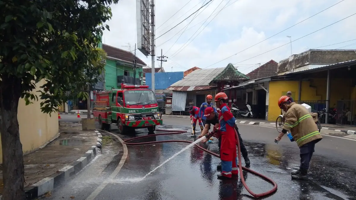 SEMPROT: Tim Damkar Satpol PP Kota Probolinggo membersihkan tumpahan solar di tikungan Palapa Gorden, Kecamatan Kanigaran, Kota Probolinggo, Rabu (22/4) siang. (DAMKAR SATPOL PP KOTA PROBOLINGGO FOR JAWA POS RADAR BROMO)