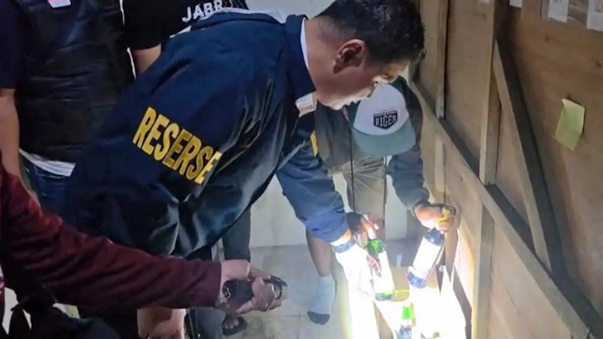 TEMUAN: Petugas Polsek Pandaan saat melakukan razia di sebuah warung kelontong yang ada di Terminal Pandaan. Hasilnya, sejumlah botol miras disita. (Polsek Pandaan for Radar Bromo)