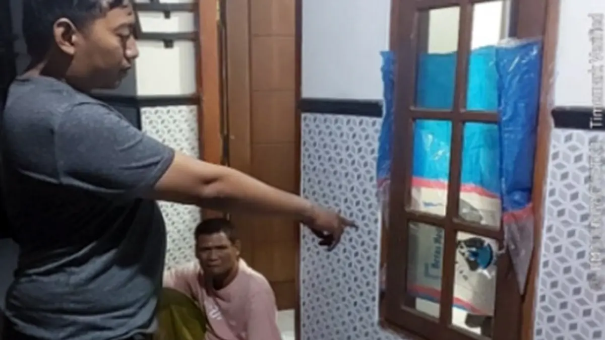 KACA PECAH: Petugas kepolisian menunjukkan jendela rumah S yang pecah usai dibondet. 