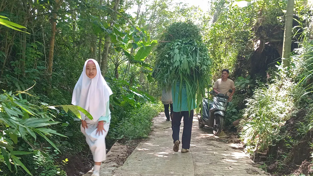 MULUS : Bendahara Desa Supardi (samping motor) menyapa warga yang beraktivitas keladang dan sekolah melewati jalan yang sudah dirabat beton diDusun pondok Klakah RT/RW 1/1. (Foto: Didik Purwanto/Jawa Pos Radar Bromo)