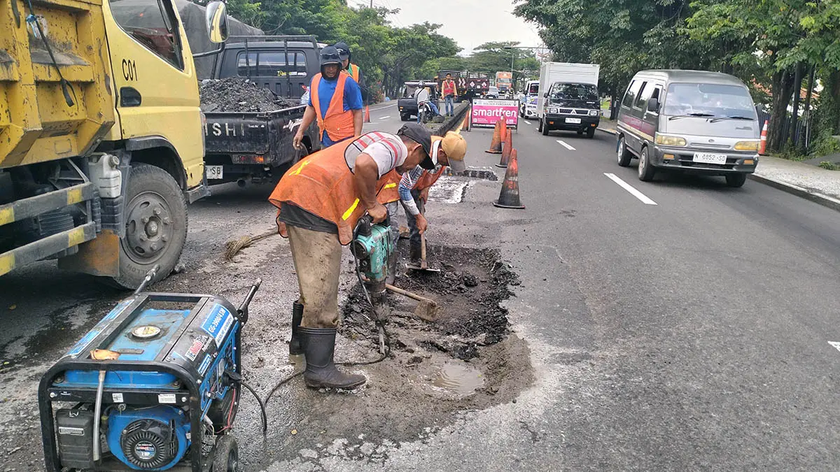 DITAMBAL: Pekerja dari BBPJN saat melakukan perbaikan jalan yang mengalami kerusakan. (Rizal Syatori/Radar Bromo)