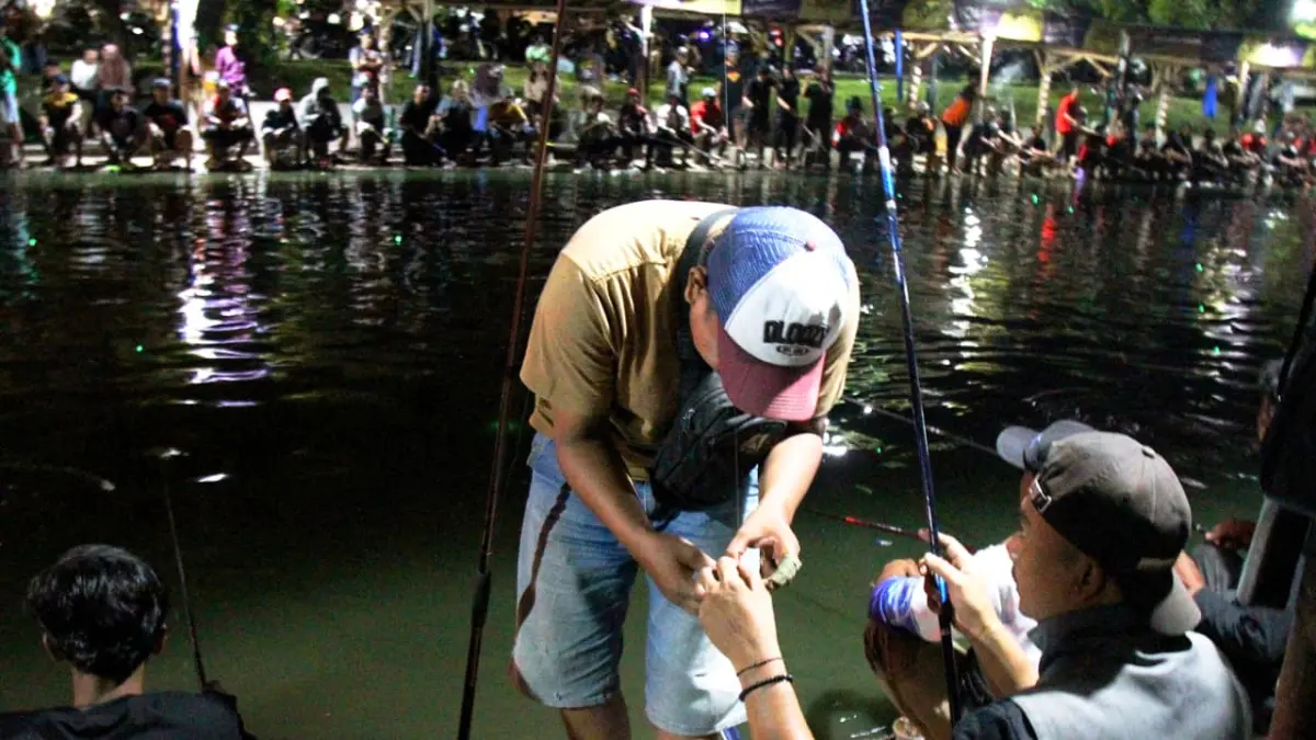 KUNCI IKATAN: Seorang pemancing umpan pada kail sebelum mulai memancing.