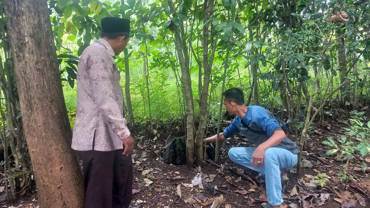 PETILASAN: Ketua Lembaga Masyarakat Desa Hutan (LMDH) Lumbang, Asmun (baju biru) bersama Sekretaris Desa Lumbang, Murtopo saat menunjukkan sebuah batu yang dipercaya sebagai alat yang pernah digunakan oleh Mbah Sentono untuk menempa gaman di Desa/Kecamatan Lumbang, Kabupaten Probolinggo. (Inneke Agustin/Radar Bromo)