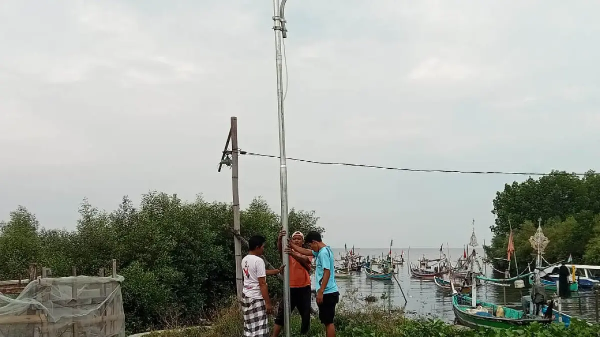 DIRATAKAN: Proses pemasangan PJU solar cell di jalan menuju laut di Desa Penunggul. (Foto : Fuad Alyzen Jawa Pos Radar Bromo)