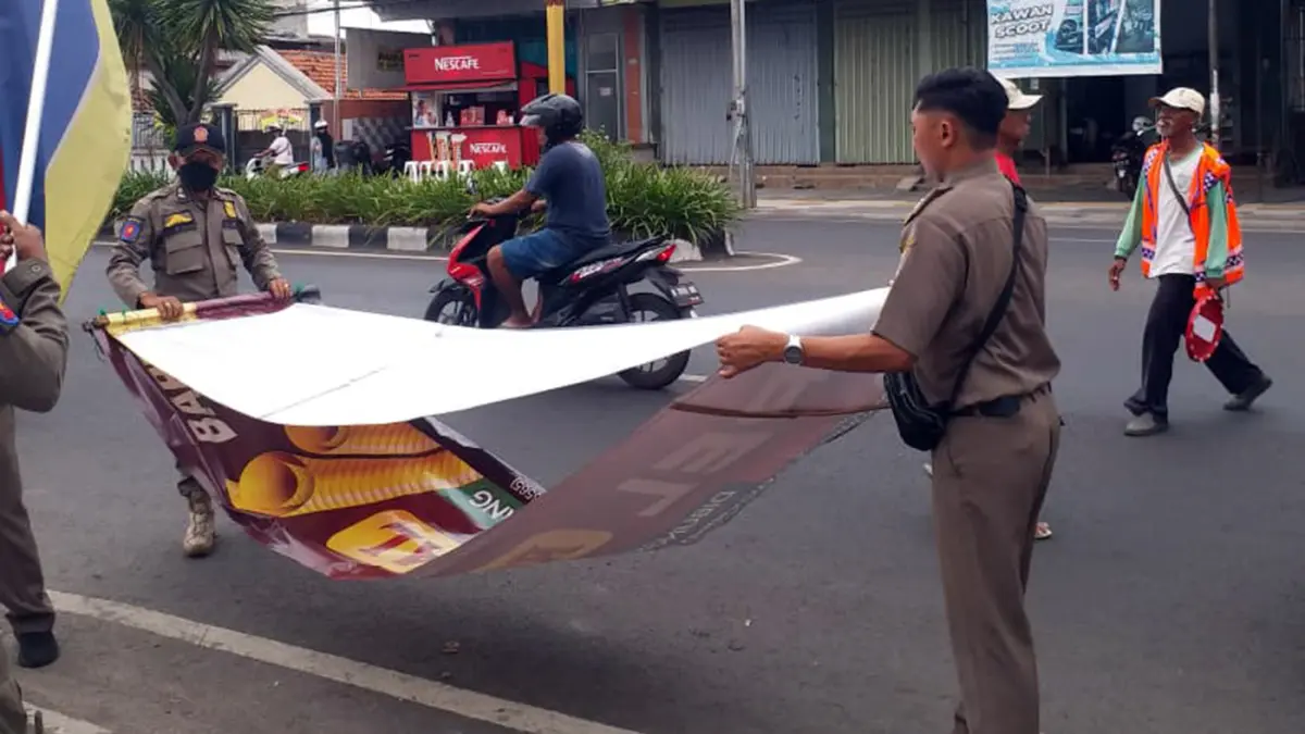 DITERTIBKAN: Petugas Satpol PP Kota Probolinggo saat melakukan penertiban reklame di Jalan Panglima Soedirman hingga Hayam Wuruk, Senin (27/4) pagi.
