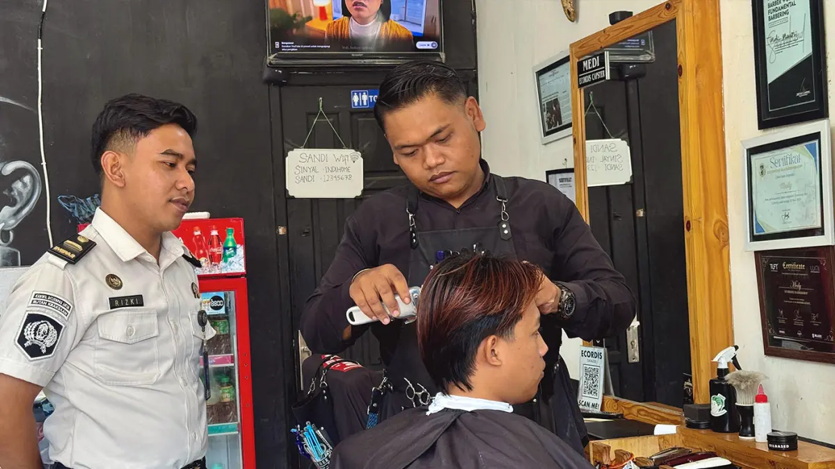 MEMANTAU: Rizki Febriyan memantau karyawannya yang sedang melayani pelanggan di usaha barbershop miliknya di Kraksaan. (Achmad Arianto/ Radar Bromo)
