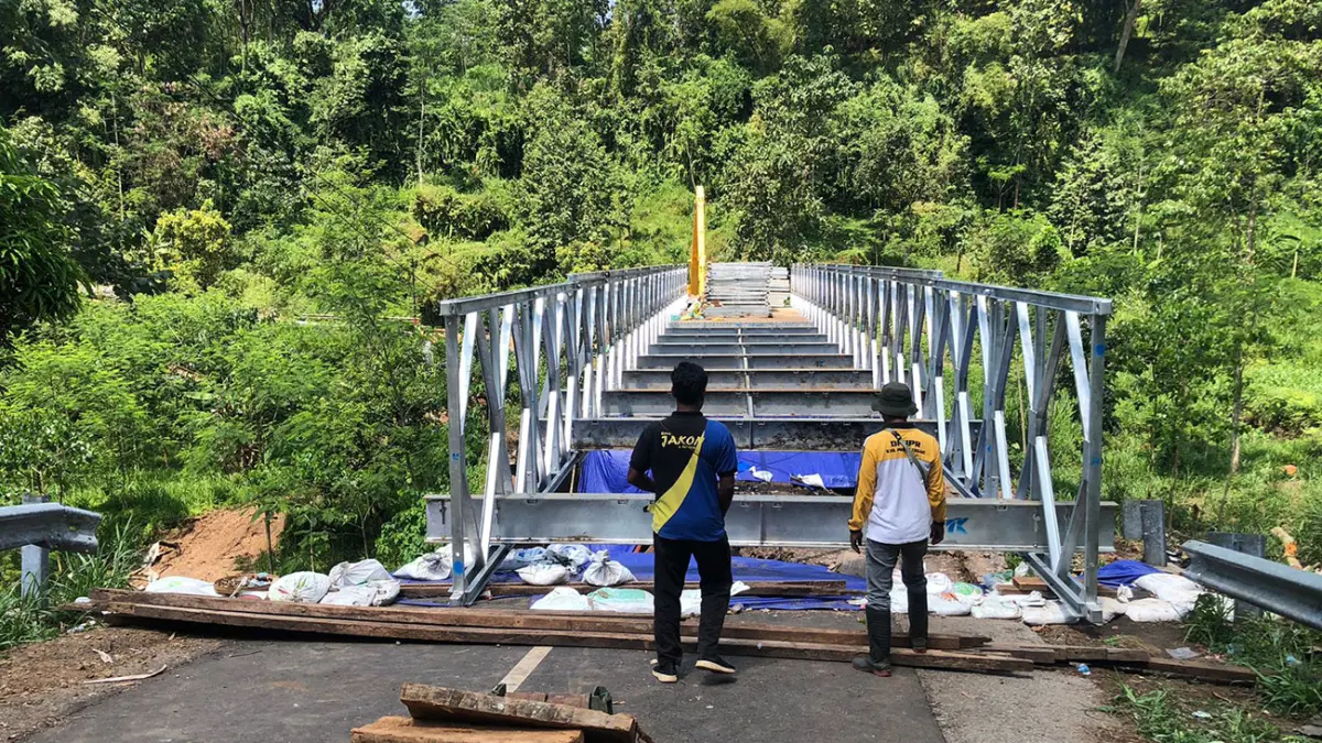 TERHUBUNG: Pekerja dari Dinas PUPR Perkim Kabupaten Probolinggo di lokasi perakitan Jembatan bailey di Desa Negororejo, Kecamatan Lumbang, Kabupaten Probolinggo, Minggu (26/4) siang. (inneke Agustin/ Radar Bromo)