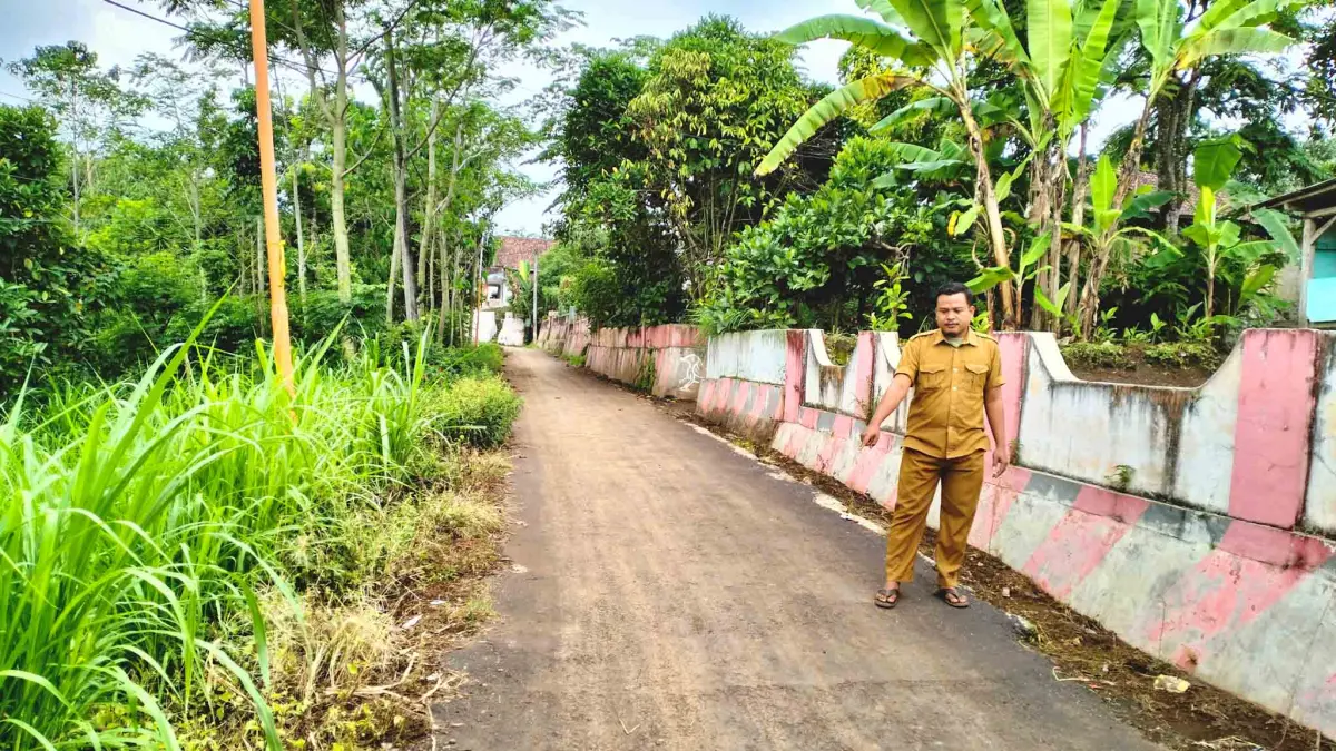 MULUS: Sekretaris Desa Wedusan Zainul Abdul Rahman mengecek ruas jalan aspal di RT 15-12/RW 4, Dusun Wedusan, yang merupakan jalan poros desa. (ACHMAD ARIANTO/JAWA POS RADAR BROMO)