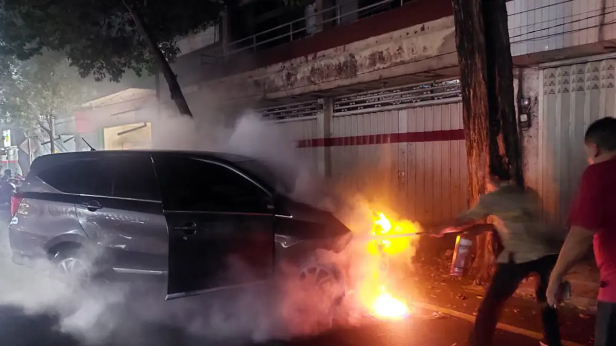AMUK SI JAGO MERAH: Kondisi mobil Daihatsu Sigra saat terbakar bagian kap depannya dipadamkan dengan apar. (Arif Mashudi/ Radar Bromo)
