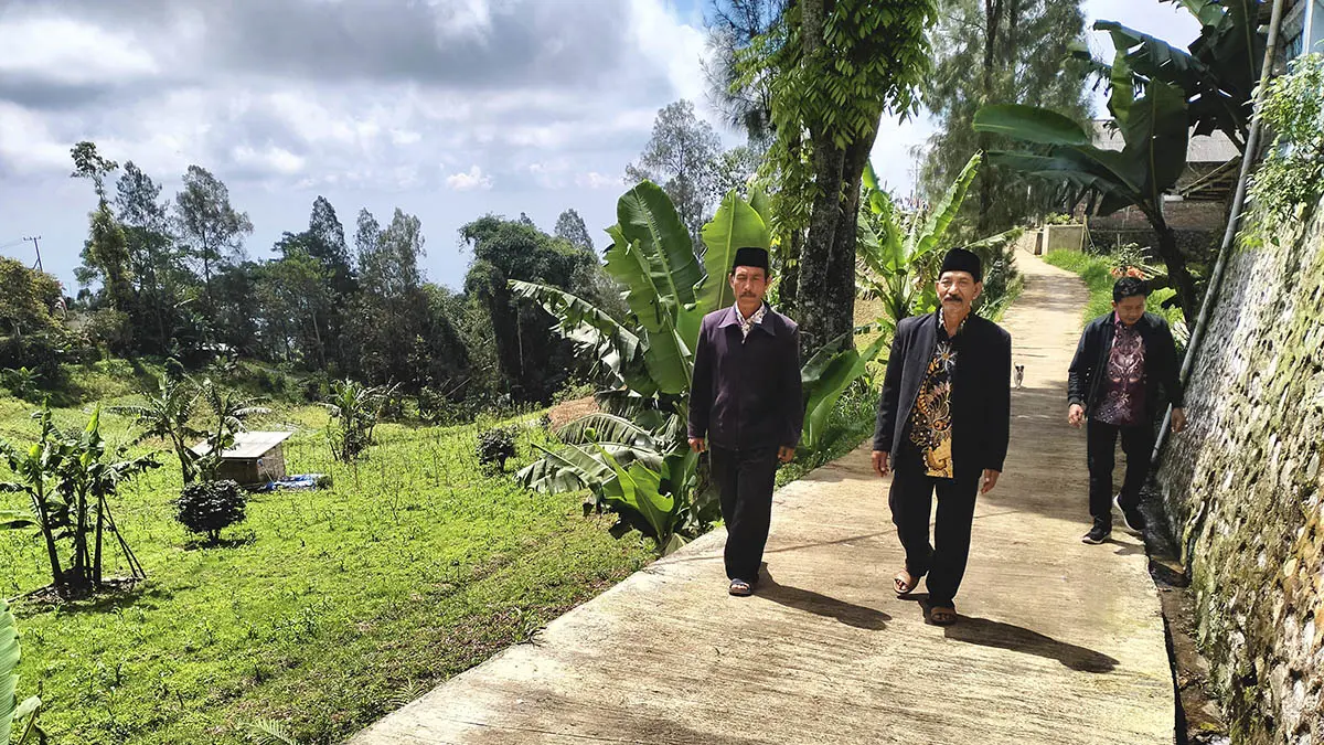 KOKOH: Kepala Desa Sariwani Sukariyo (tengah) berjalan di jalan rabat beton RT 5/RW 3, Dusun Kertowani yang selesai dibangun tahun 2025. Pembangunan infrastruktur hingga kini masih jadi prioritas.&nbsp;(Foto: Achmad Arianto/Jawa Pos Radar Bromo)