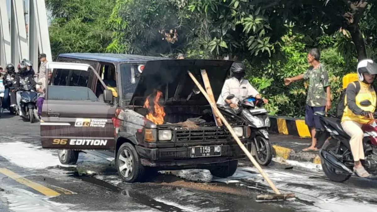 JALAN MACET: Mobil Kijang bernopol N 1159 MD di jalur Pantura wilayah barat Jembatan Paiton, yang terbakar Jumat siang (8/5). Peristiwa itu sempat membuat arus lalu lintas tersendat lantaran warga dan pengendara berusaha melihat kejadian dari tepi jalan. (Foto: Agus Faiz Musleh/Jawa Pos Radar Bromo) 