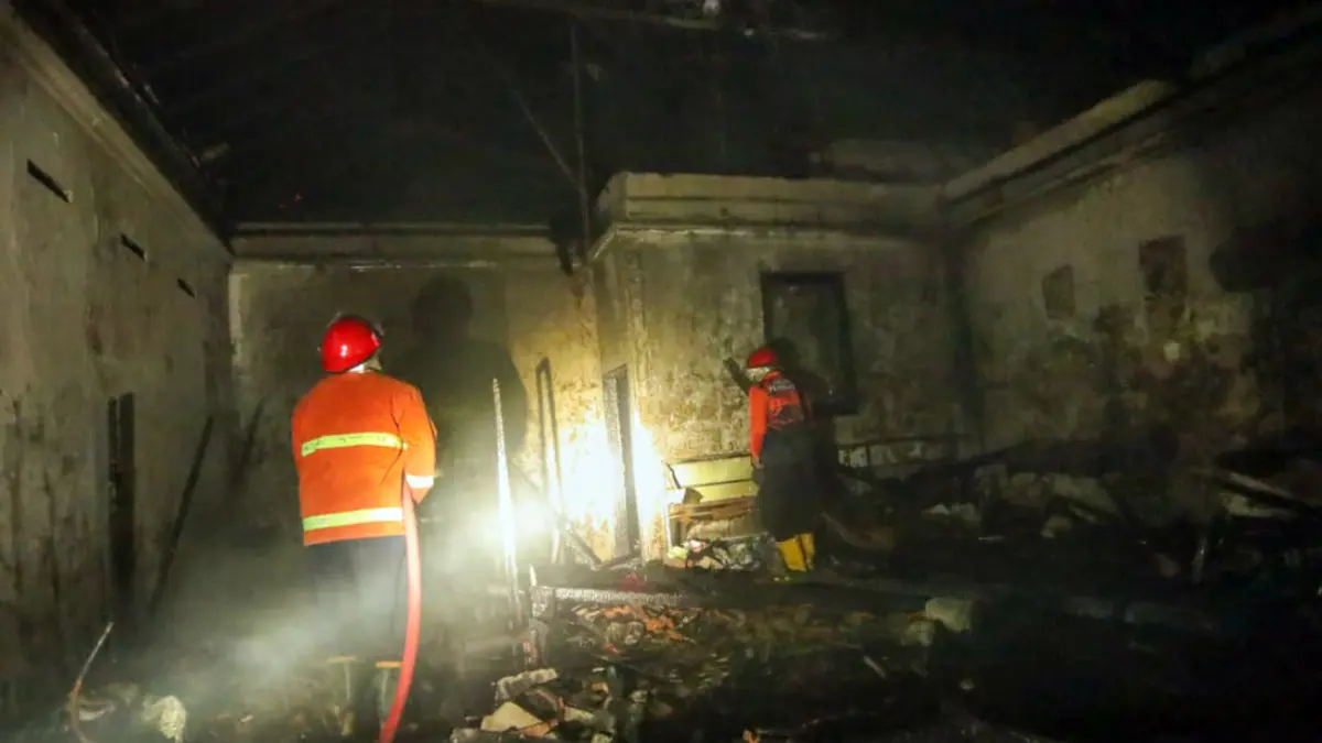 Petugas melakukan pembasahan pada rumah dan salon Citra di Tapaan, Bugul Kidul, Kota Pasuruan yang terbakar. (Mokhamad Zubaidillah/ Radar Bromo)