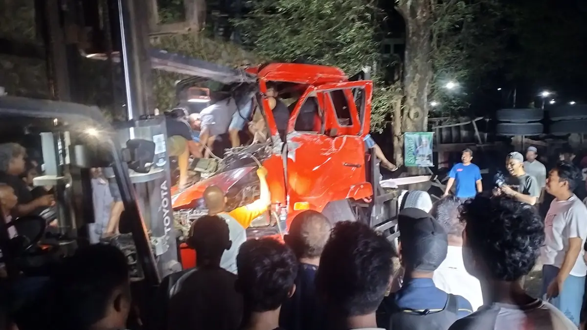 TERJEPIT: Petugas Satlantas Polres Pasuruan dibantu warga sekitar mengevakuasi sopir dan kernet truk kontainer secara bergantian. Kernet dievakuasi dari parit dan sopir yang terjepit dievakuasi dari ruang kemudi, Selasa (12/5) malam. (Rizal Syatori/ Radar Bromo)