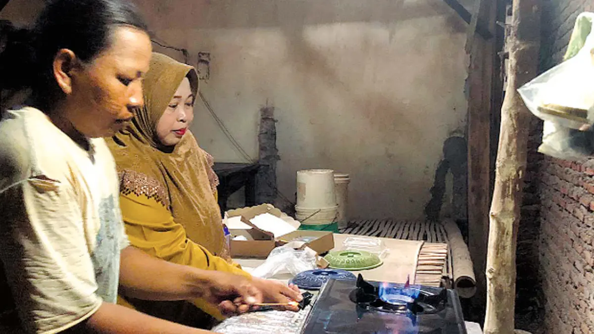 HEMAT ENERGI: Ketua TP PKK Desa Watuwungkuk Listiyawati (berkerudung) mencoba hasil gas yang berasal dari pengolahan kotoran sapi di Desa Watuwungkuk.
