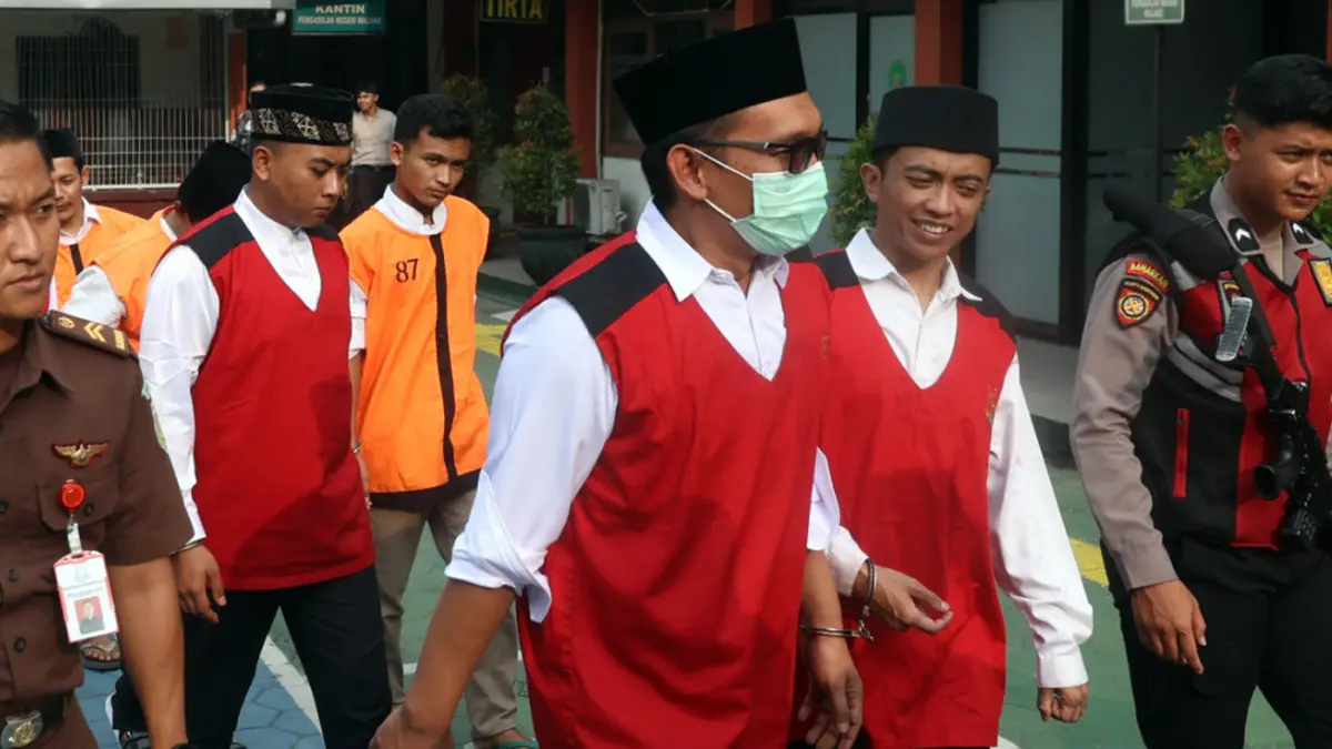 RAJA TEGA: Terdakwa Agus Saleman (pakai masker) saat hendak mengikuti sidang perdana pembunuhan adik ipar, di PN Malang, (20/5). (Darmono/ Radar Malang)
