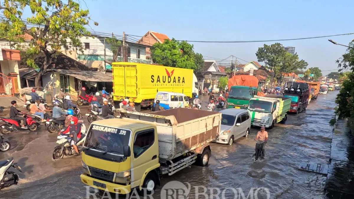 RENDAM JALAN NASIONAL: Sejumlah kendaraan melintas di jalan pantura Tambakrejo, Kraton, Kabupaten Pasuruan yang terendam banjir. (Mokhamad Zubaidillah/ Radar Bromo)