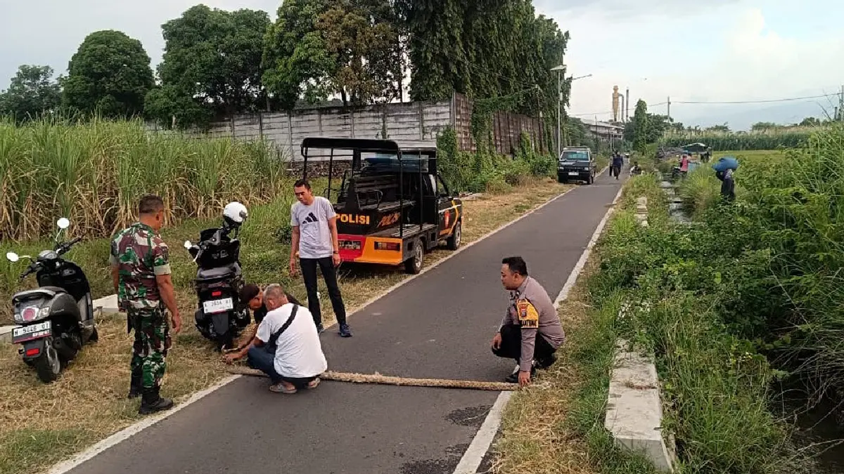 PASANG: Anggota Polsek Kademangan, Polres Probolinggo, memasang tali kejut di Jalan Kerinci, Kelurahan Pilang, Kecamatan Kademangan. (POLRES PROBOLINGGO KOTA FOR JAWA POS RADAR BROMO)