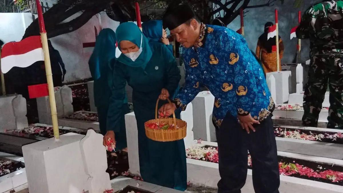 KHIDMAT: Bendahara Desa Kalirejo Nanang Wahyudi bersama istri melakukan tabur bunga di Makam Pahlawan R. Soejoso, Desa Kalirejo, Kecamatan Dringu.