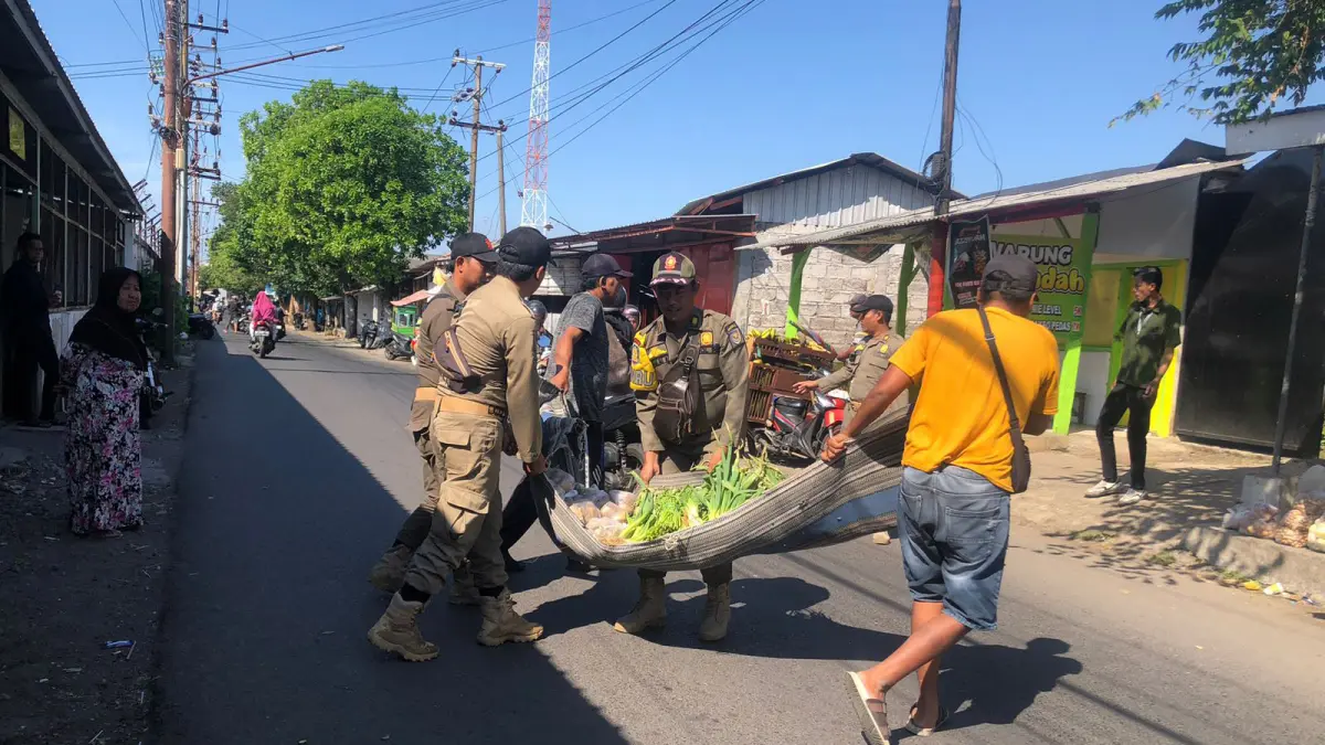 RELOKASI: Anggota Satpol PP Kota Probolinggo membantu salah seorang pedagan memindah dagangannya di Jalan Supriadi, Kelurahan/Kecamatan Kanigaran, Jumat (29/5).&nbsp;(INNEKE AGUSTIN/JAWA POS RADAR BROMO)