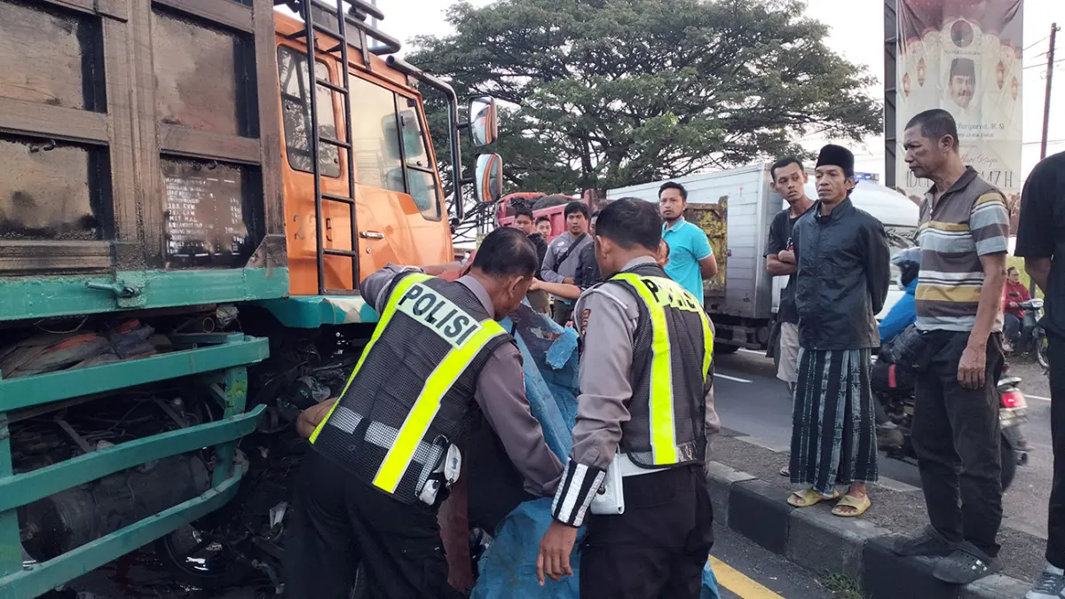 NAHAS: Petugas saat mengevakuasi korban usai tertabrak truk yang baru keluar dari SPBU. (Rizal Syatori/ Radar Bromo)