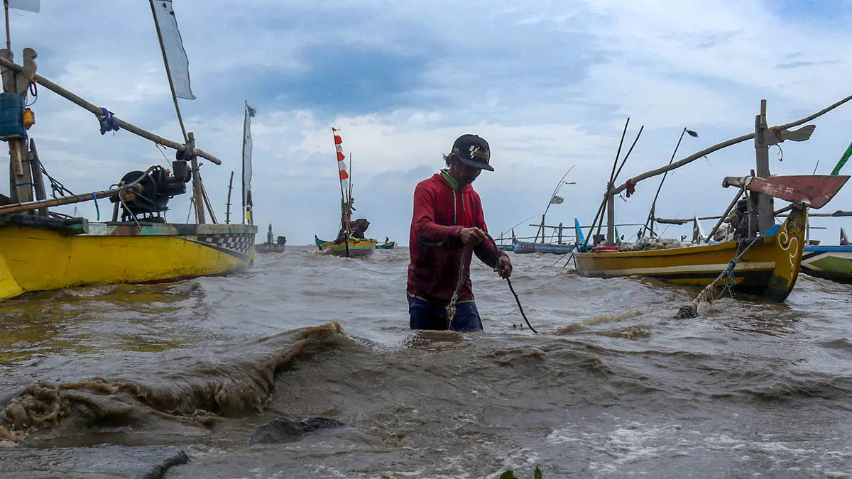 ANCAMAN: Nelayan di persisir Lekok menepikan perahunya ke tepi pantai saat ombak tinggi. (Foto: dok Jawa Pos Radar Bromo)