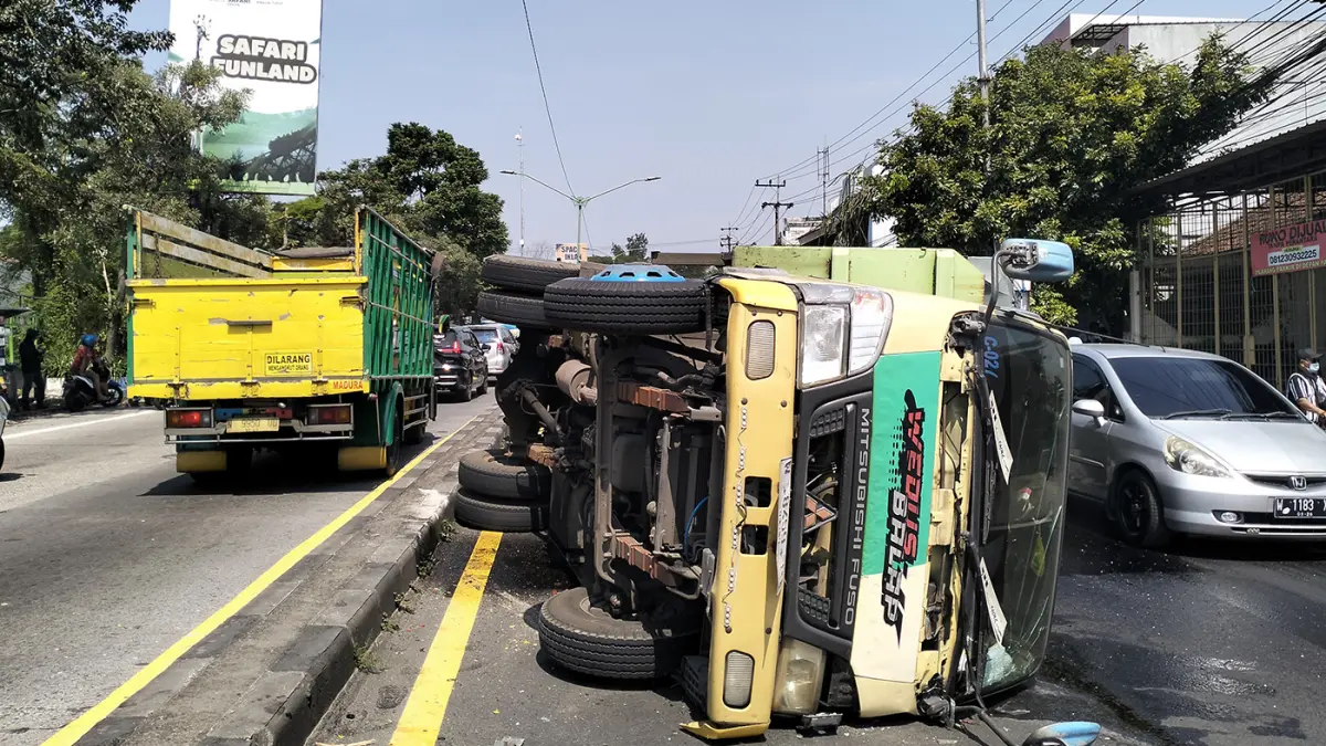 Kondisi truk terguling usai tertabrak dump truck di utara simpang empat patung sapi Pandaan.  