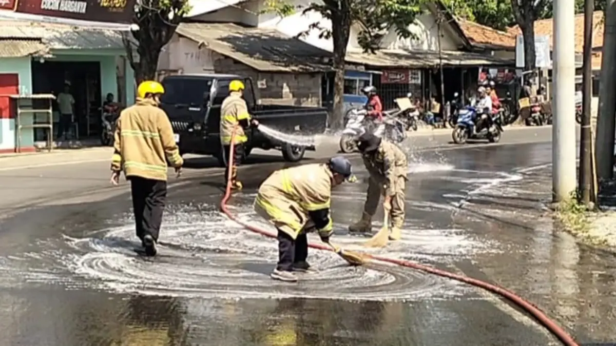 SIRAM: Petugas Damkar Kabupaten Probolinggo saat melakukan pembersihan ceceran oli di Jalan Raya Bromo, Desa Patalan, Kecamatan Wonomerto, Rabu (3/6) siang.