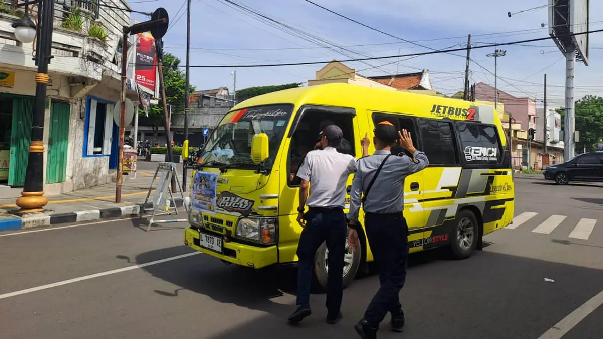 HALAU: Petugas Dishub Kota Pasuruan saat melakukan pengaturan kendaraan yang melintas di wilayah Kota Pasuruan. (Fuad Alyzen/Radar Bromo)