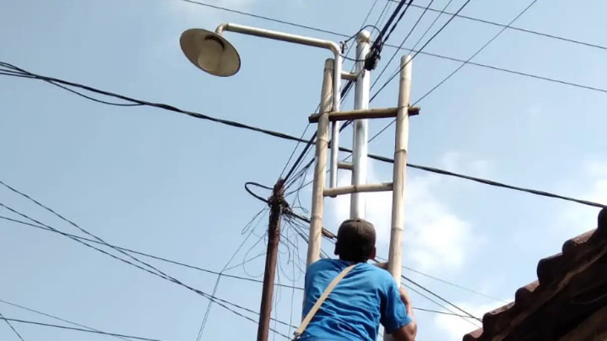 LEBIH AMAN: Seorang petugas mengecek salah satu PJU yang dipasang di jalan Desa Gunggungan Lor. (PEMERINTAH DESA GUNGGUNGAN LOR FOR JAWA POS RADAR BROMO)