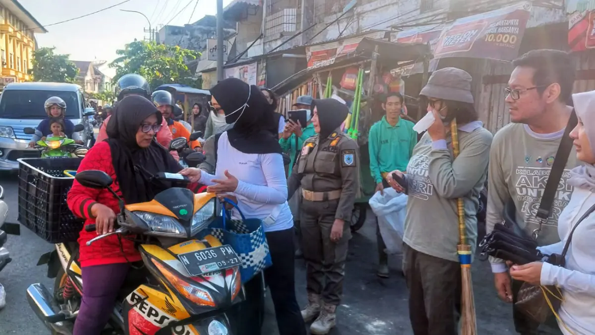 BAGI TAS: Ketua TP PKK dr. Evariani saat membagikan kanting tas belanja ramah lingkungan bagi pengguna jalan usai aksi bersih-bersih.        