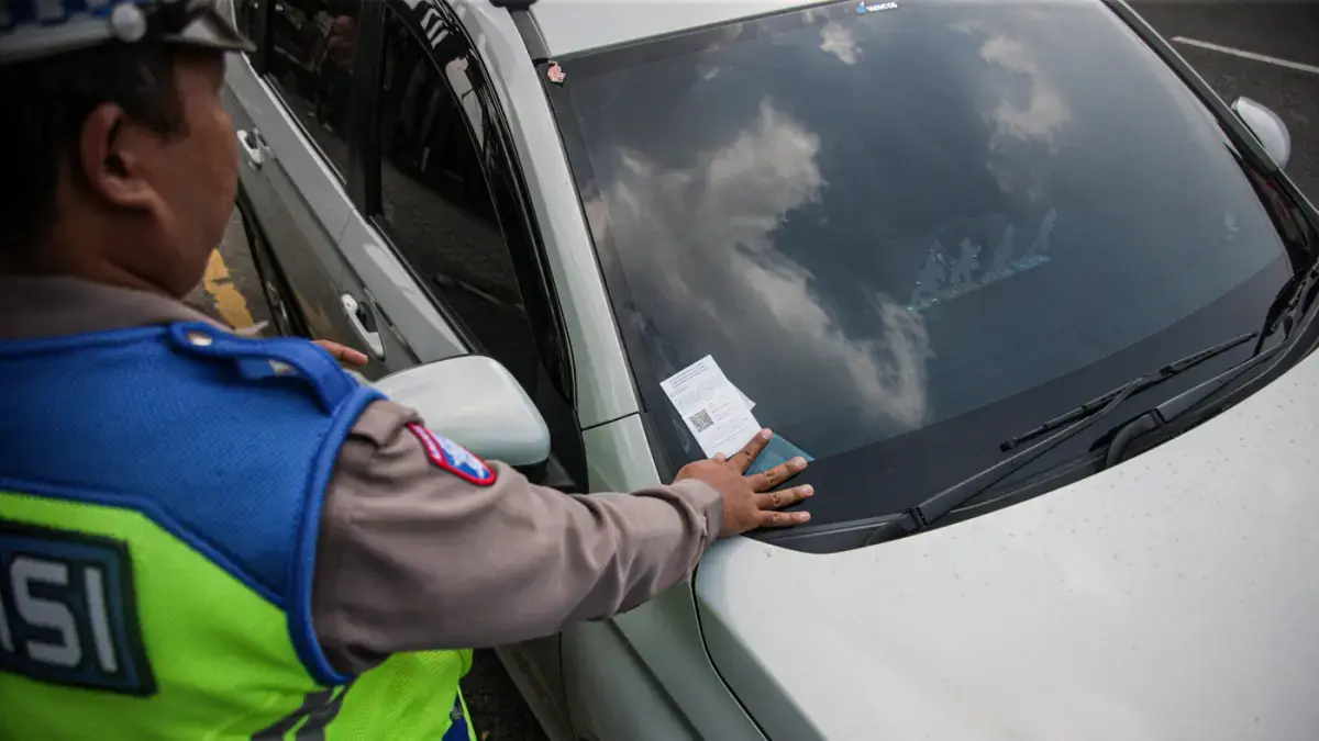 Anggota Satlantas Polres Metro Tangerang Kota melakukan pendindakan parkir liar dengan tilang ETLE Handheld di jalan Daan Mogot, Kota Tangerang, Kamis (07/05/2025). (Hanung Hambara/Jawa Pos)