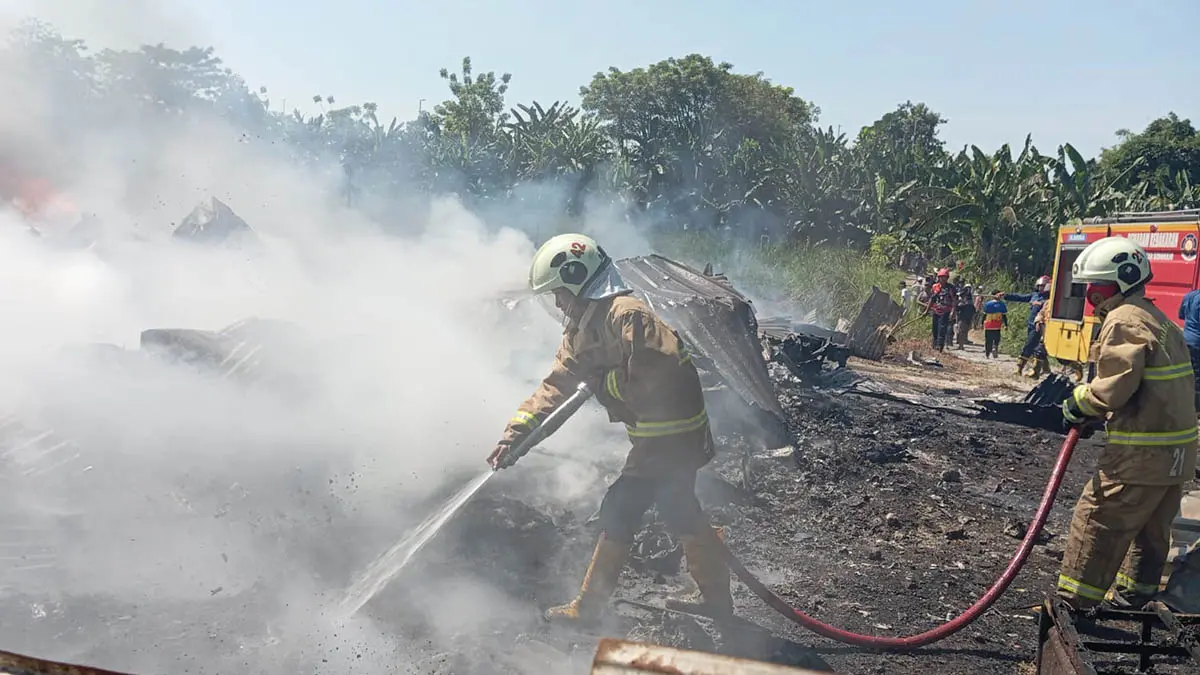 PEMBASAHAN: Personel damkar memadamkan api yang membakar gudang. (Foto: Polres Pasuruan for Jawa Pos Radar Bromo)
