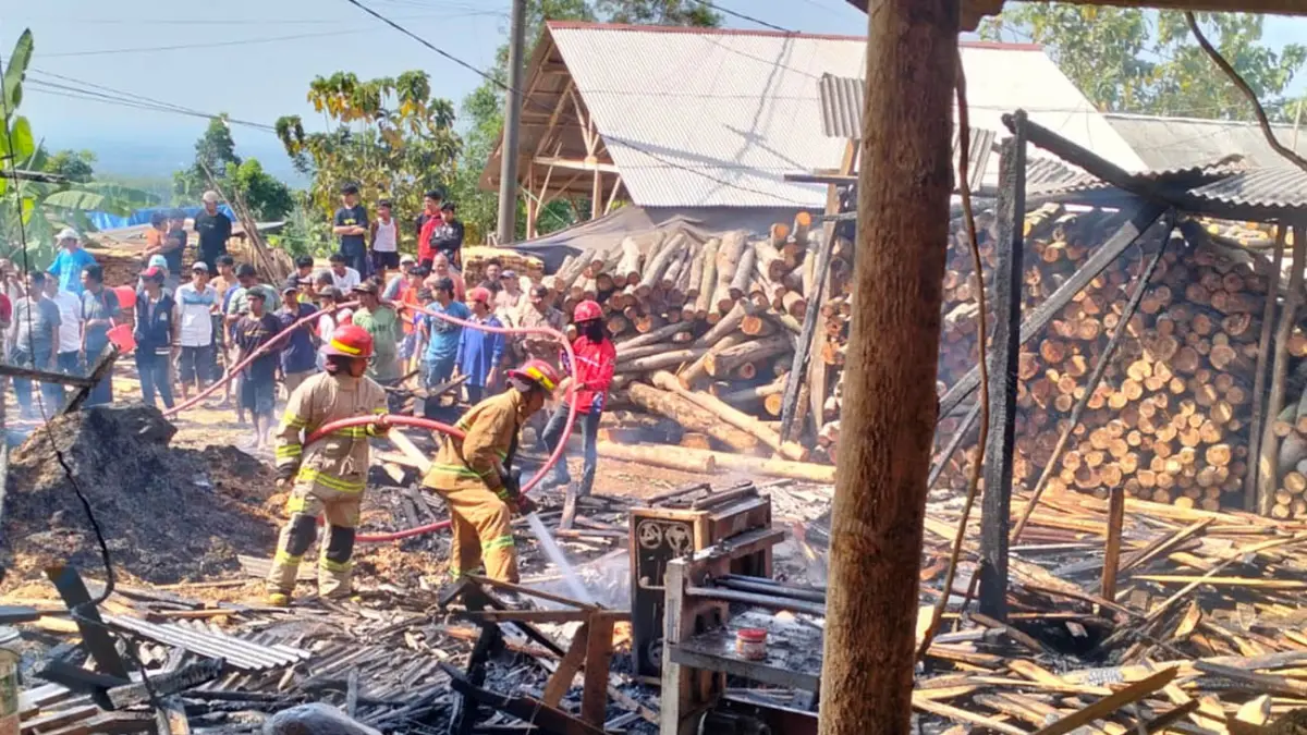 AMUK SI JAGO MERAH: Petugas damkar saat melakukan pembasahan pada tempat produksi palet kayu yang terbakar di Kuripan, Probolinggo. 