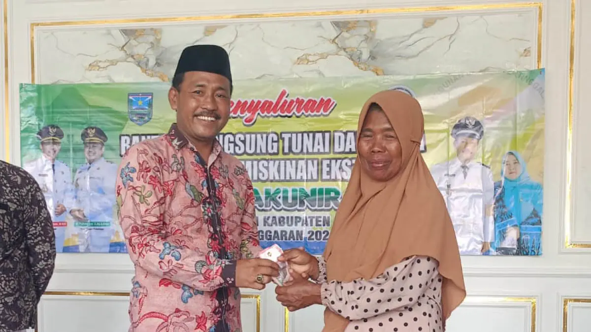 BANTUAN: Kepala Desa Pakuniran Ahmad Fauzi menyerahkan BLT DD Kemiskinan Ekstrem kepada warga penerima manfaat. (Foto: Didik Purwanto/Jawa Pos Radar Bromo)