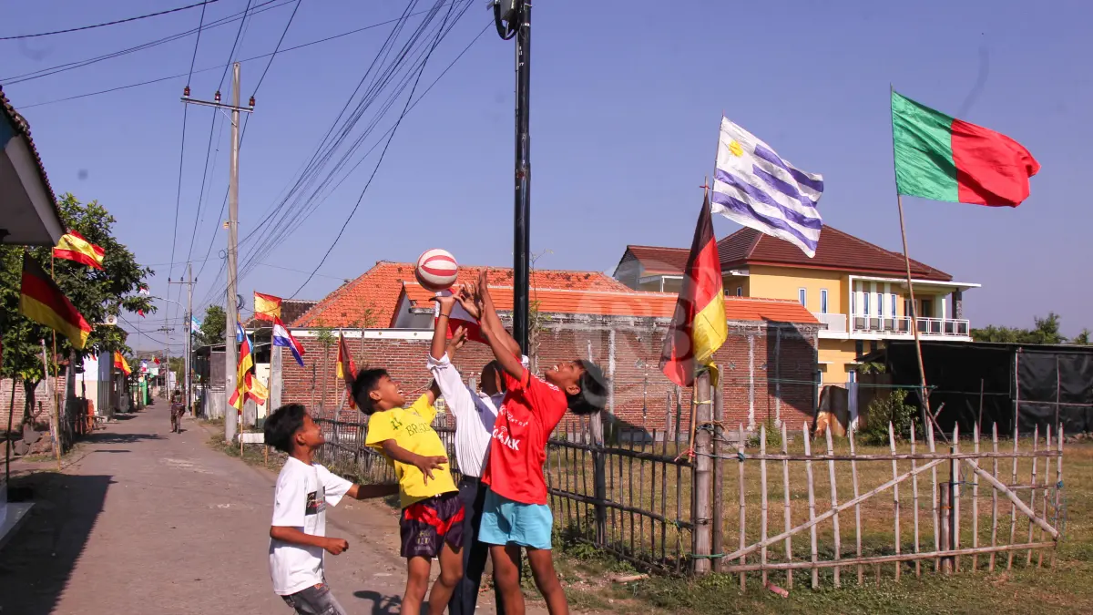 SPIRIT FOOTBALL: Sejumlah bocah di Desa Gerongan bermain sepakbola. Nampak banyak bendera negara peserta piala dunia yang dipasang. (Foto: M Zubaidillah/Jawa Pos Radar Bromo)