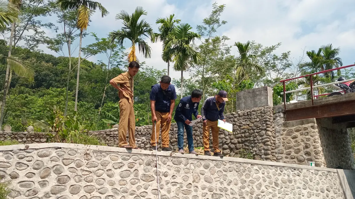 UKUR: Tim monitoring evaluasi Kecamatan Pakuniran didampingi bendahara Desa Kedungsumur Slamet mengecek pembangunan TPT Dusun Kalianyar RT/RW 1/1. (Foto: Didik Purwanto/Jawa Pos Radar Bromo)